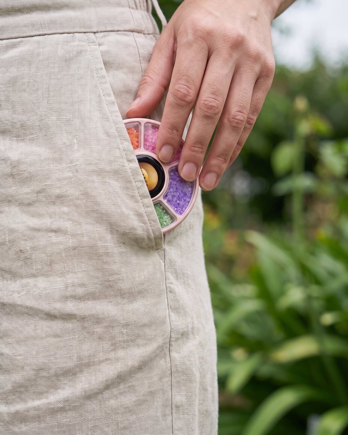 The blush-pink dial peeking from the pocket of linen trousers in a garden